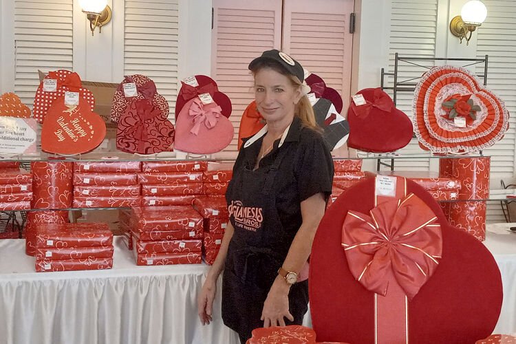 Lisa Thatcher, a 45-year Aglamesis employee, stands beside the store's prominent display of Valentine's Day candy boxes.
