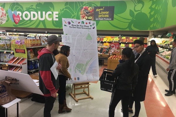 Walnut Hills residents discuss a graphic showing neighborhood food resources installed by WHRF at soon-to-close Kroger location.