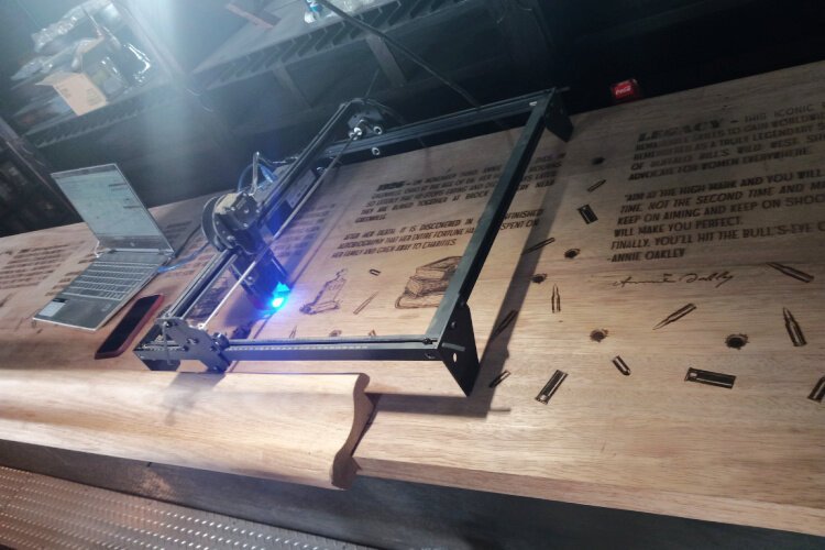 Annie Oakley’s employee Britton de la Chapelle etched graphics into the establishment’s signature mahogany bar which highlight the legend of its namesake.