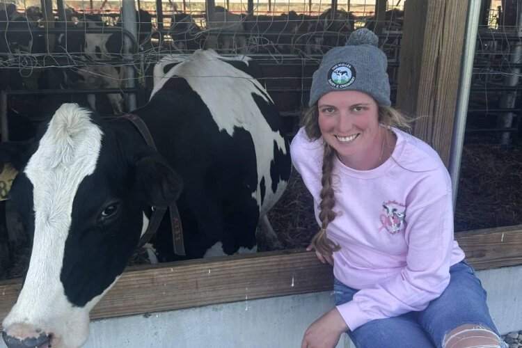 Emily Mullen, a 4th-generation farmer who operates Mullen Dairy and Creamery in Okeana, poses with one of her herd. Even with a robotic milker, a cycle of upkeep and tending to bovine births and illnesses makes it far more than a full-time job.