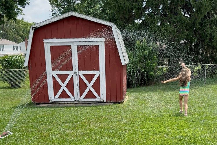 Joelle B., 7, running through a sprinkler.
