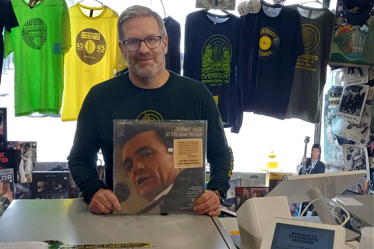 Woody Dorsey, Everybody’s Records owner and a 30-year store veteran, first lured into music by watching a televised Johnny Cash performance, poses with an album of the Man in Black’s work.