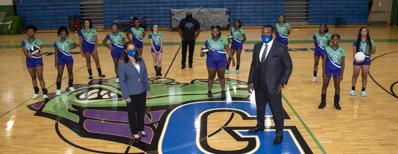 The girls volleyball team at Gamble High School practicing in the gym with Assistant Principal Kynda Few on the left and Principal Taylor Porter on the right.