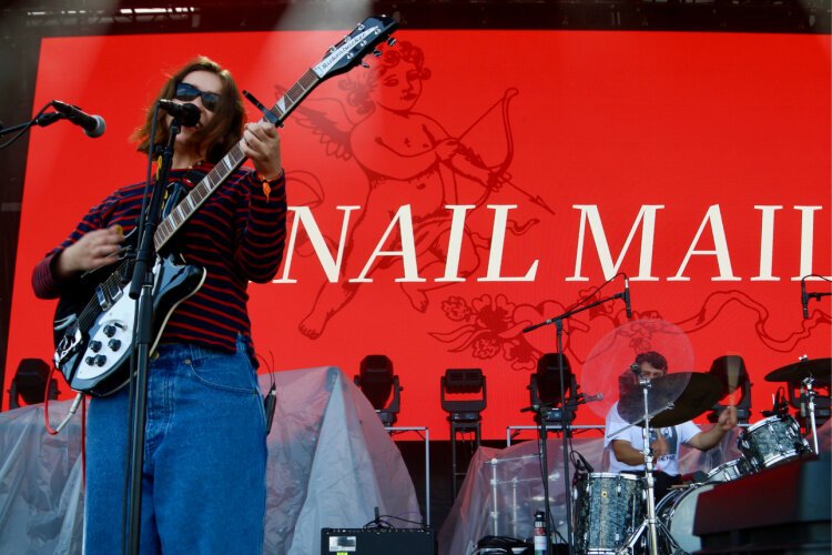 Snail Mail singer/songwriter Lindsey Jordan playing her Rickenbacker guitar with drummer Ray Brown in the background.