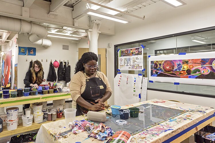 Studio artists Kelsey Wood (foreground) of Madisonville and Lauryn Campbell of Clifton work on a piece for Thermo-Fisher Scientific’s Cincinnati office.