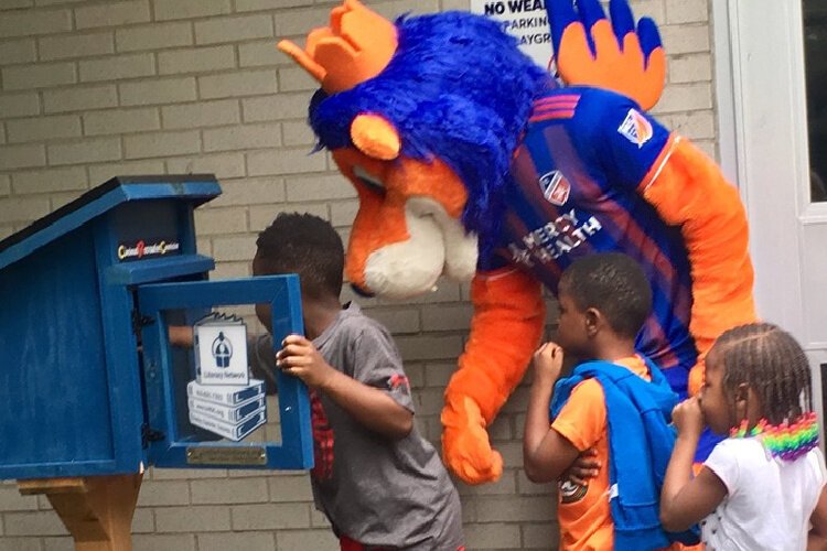Children wait their turn to look through the Little Free Library at the Cincinnati Recreation Center in Millvale, installed by the Literacy Network of Greater Cincinnati.
