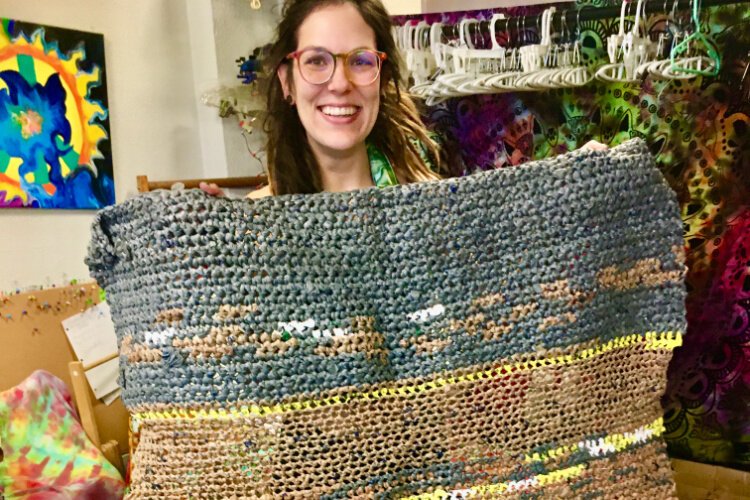 Stephanie Zier holds up a woven mat made from plastic shopping bags. She donates the mats to help make homeless Cincinnatians more comfortable while keeping bags out of landfills.