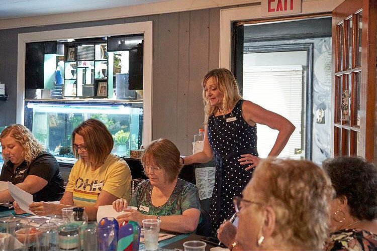 Angela Regan (standing) at Welcome Home SIS fundraiser with guests (from left) Emily Vigue from the Foundation for Appalachian Ohio, Lana Perry from Perry insurance, and Toni Kellar from Newsight Life.