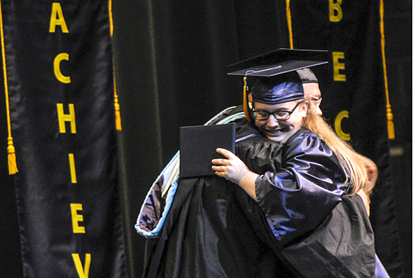 Katie Stanton receives her diploma and hugs DPCR Principal Andrew Farfsing