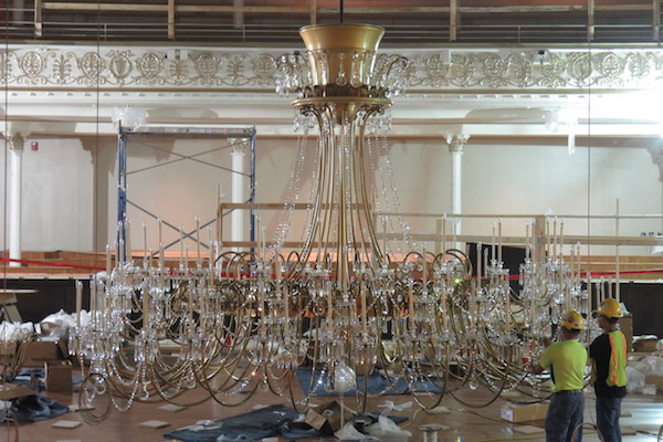 Workers reinstall a crystal chandelier following Springer Auditorium restoration.