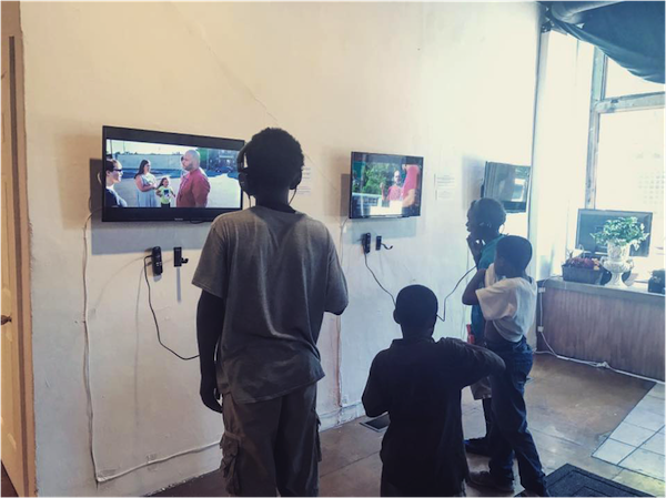 A group of kids listens to stories in the gallery.