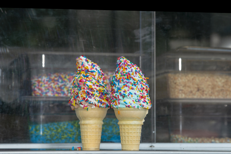 A vanilla and chocolate twist and a and blueberry, both topped with sprinkles.