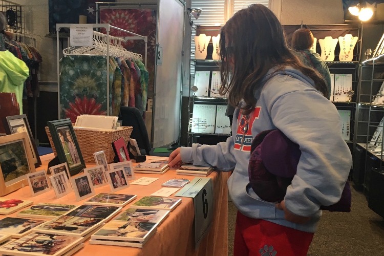 A visitor checks out tiles at artist Connie Springer’s booth.