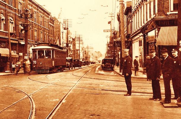 1910s-1920s-era photo shows a bustling streetcar stop and Peeble's Corner commercial district.