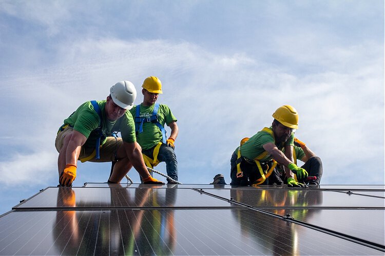 Workers from Sustainergy Cooperative, a business in the Co-op Cincy network, install solar panels.