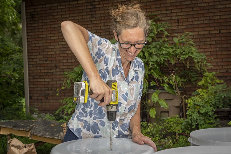 Working in Neighborhoods staffer Heather Sayre drills drainage holes in a planting starter kit.